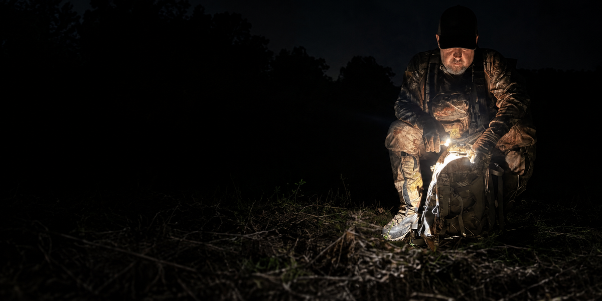 Hunter using a white DEX FingerLight while checking a pack outdoors at night
